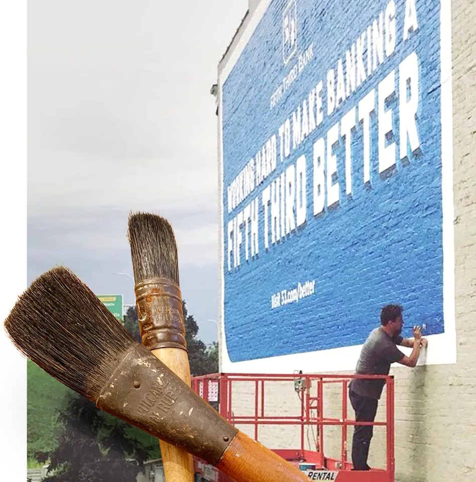 Painter on a lift painting an exterior wall ad with blue paint